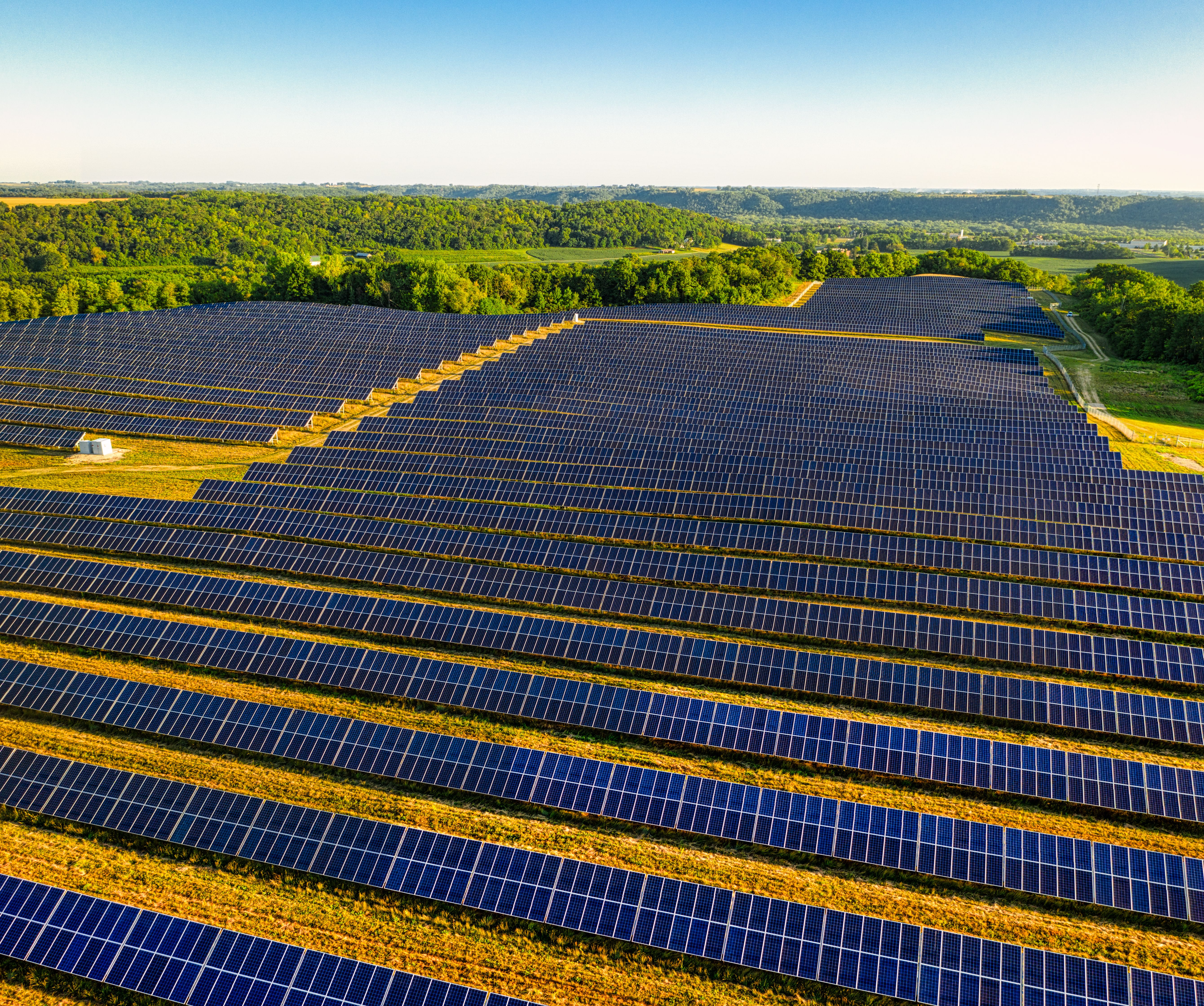 Aerial view of a large utility-scale solar array set among fields and hills